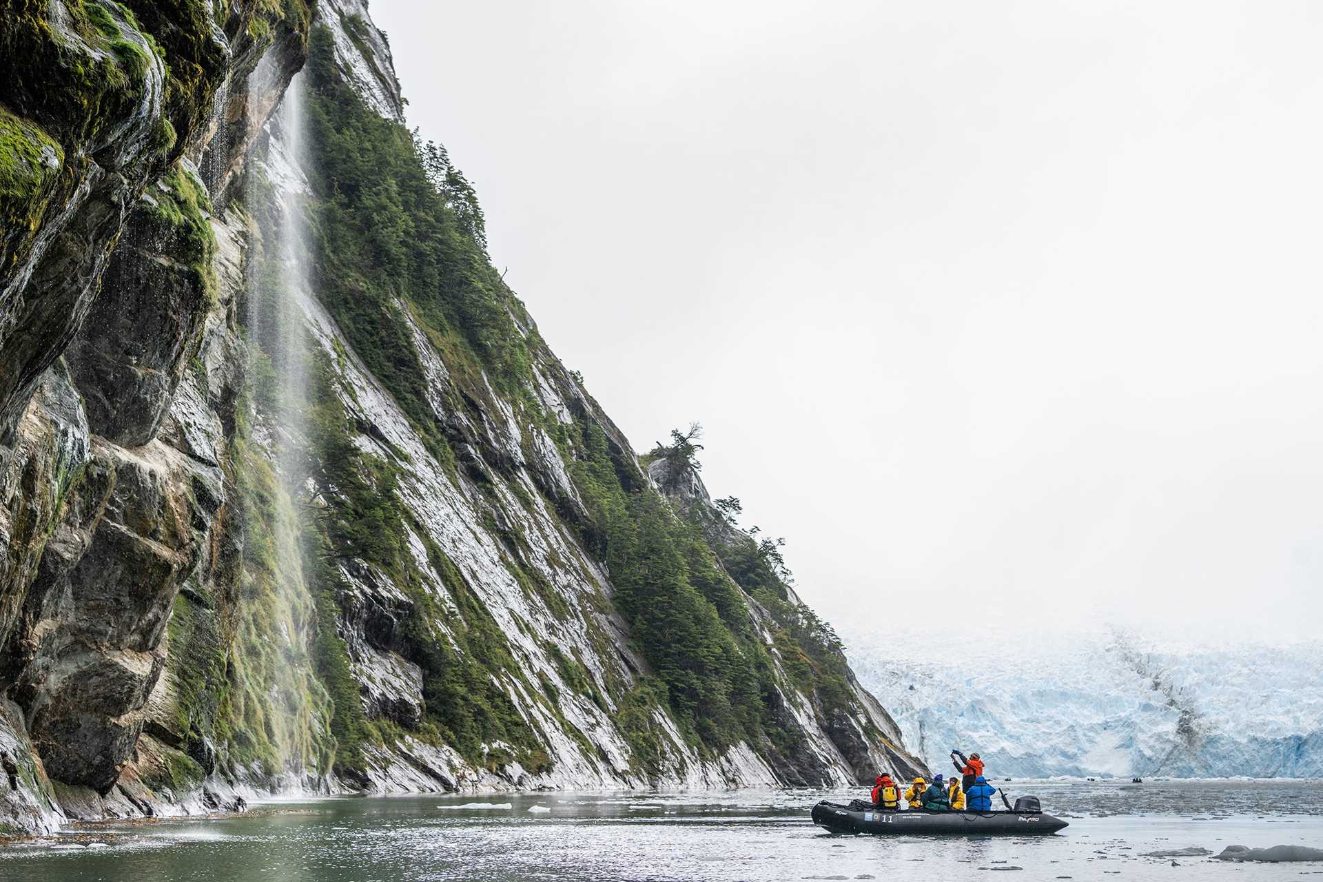 Guests in a Zodiac photograph a waterfall in Beagle Channel, Patagonia.