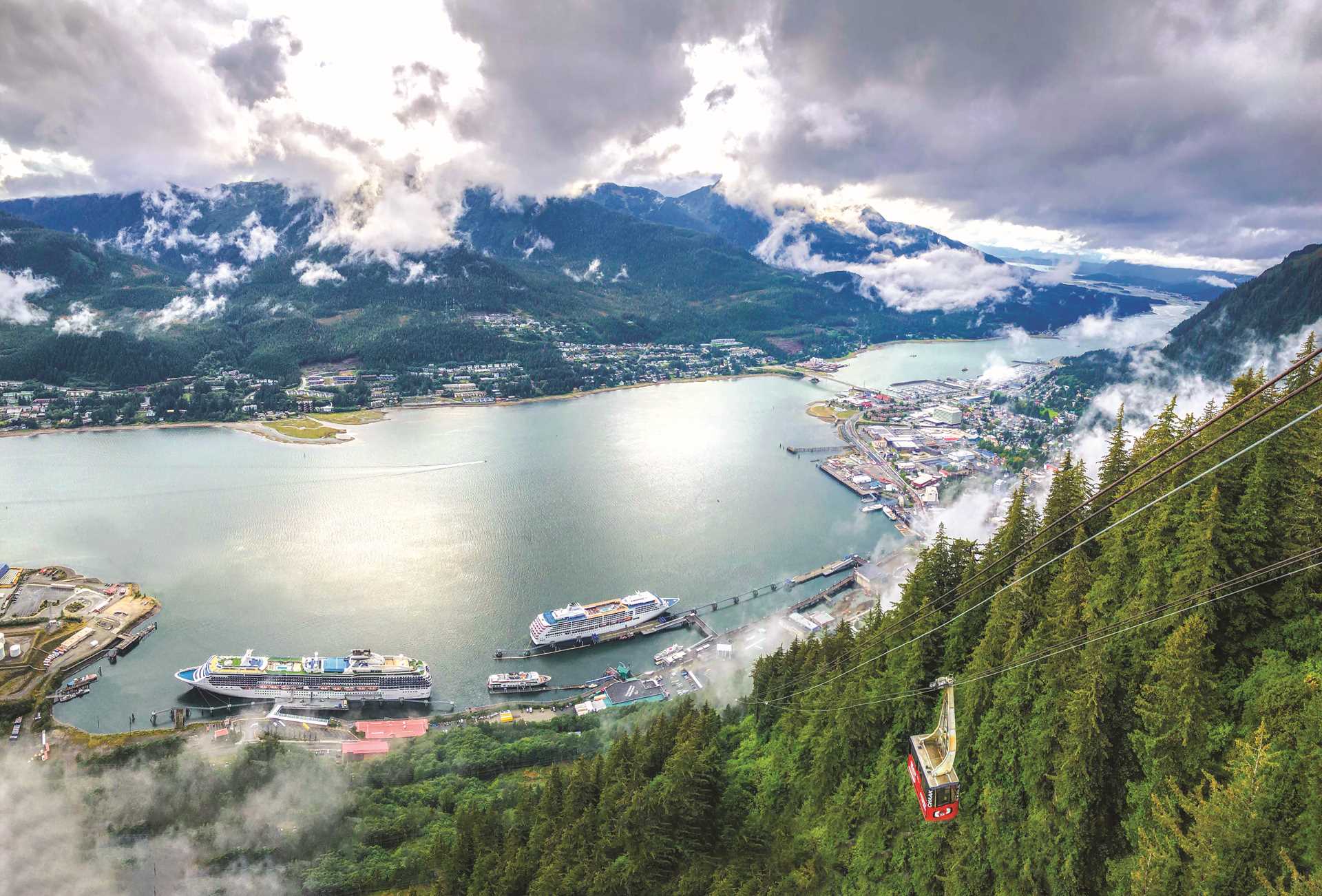 An aerial view of the National Geographic Venture in Juneau, Alaska surrounded by two large cruise ships.