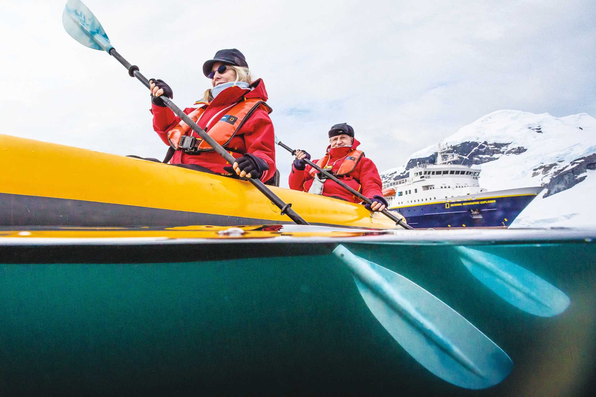 Guests kayak through the Errera Channel with the National Geographic Orion in the distance.