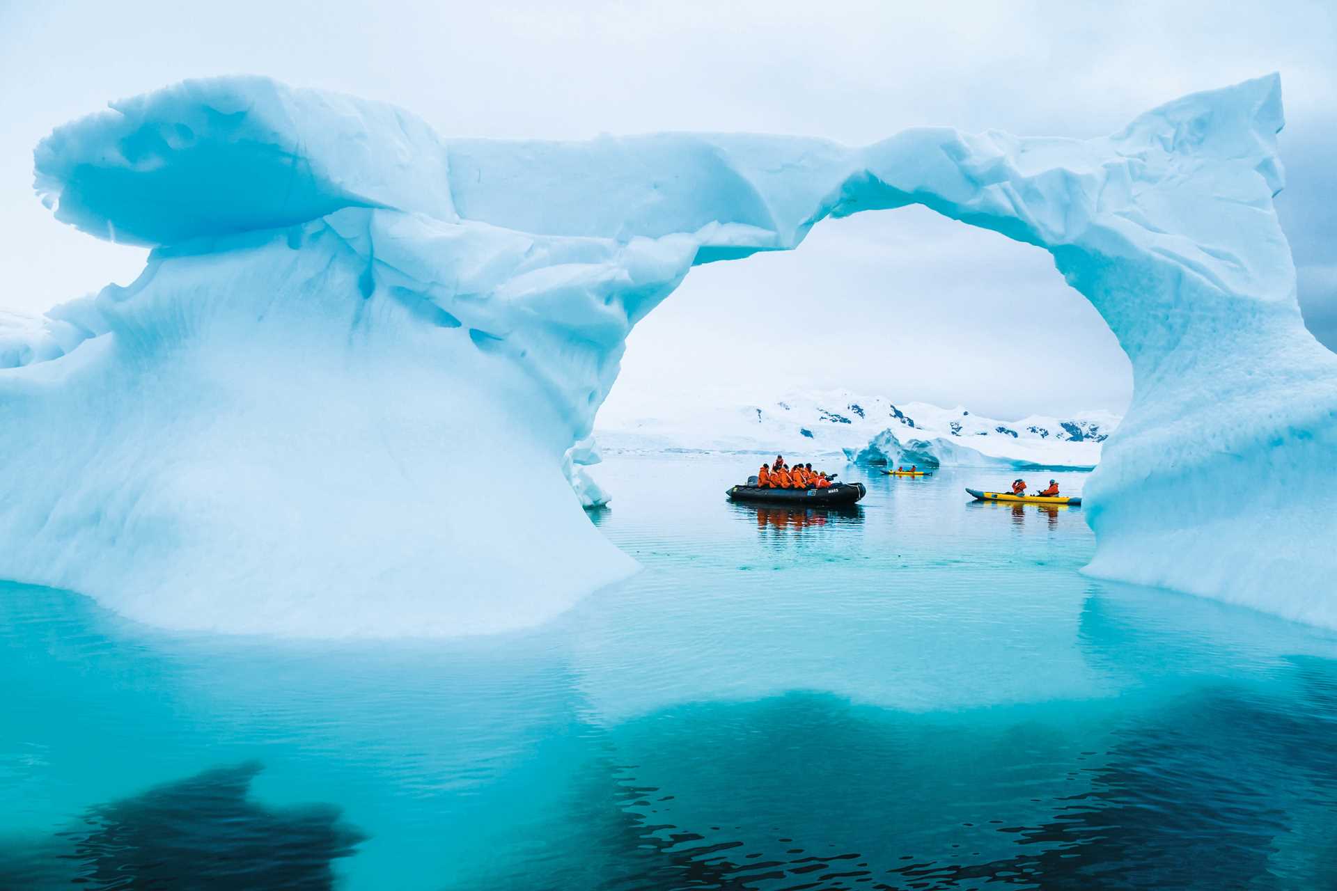 A Zodiac and a kayak parked under an ice arch in Neko Harbor.